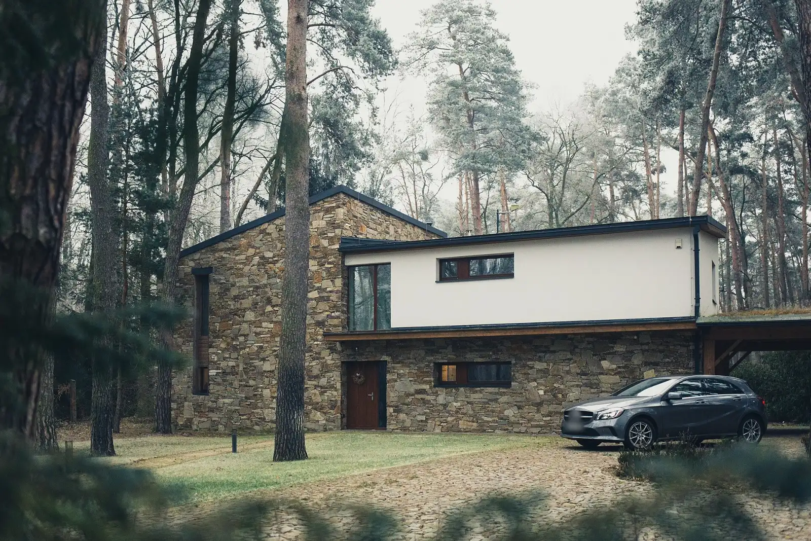 Ağaçlar arasında taş ve beyaz sıvalı villa